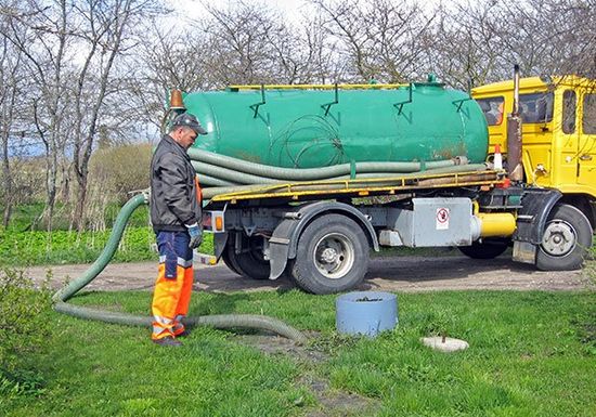 Worker collecting waste from the septic tank in Corbin