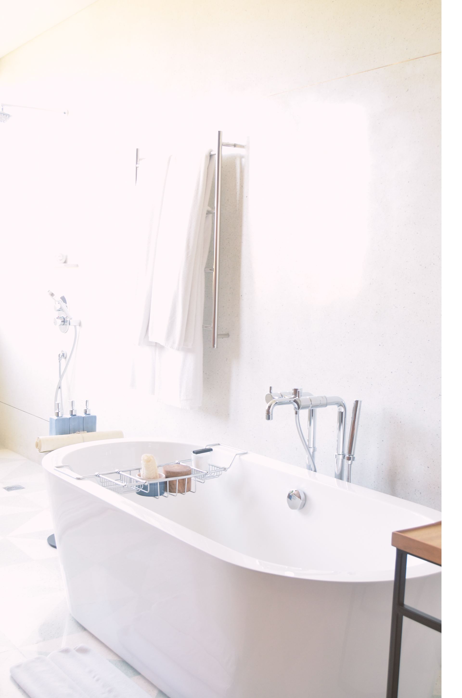 A white bathtub in a bathroom next to a window