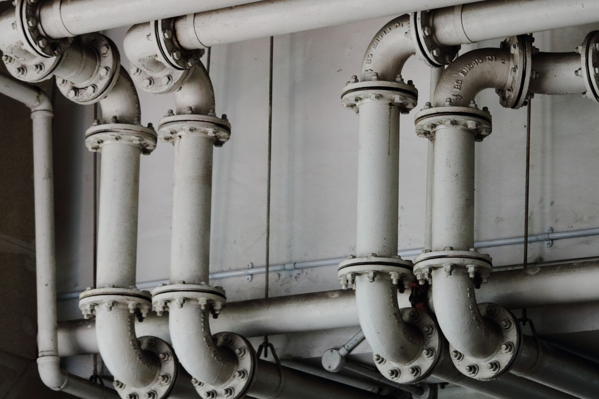 A row of white pipes hanging from the ceiling of a building.