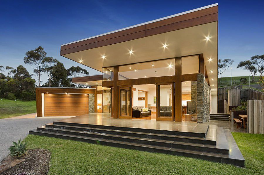 Modern home with a dramatic skillion roof, large glass doors, stone detailing and an attached garage.