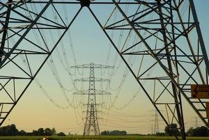 A bunch of power lines are going through a field.