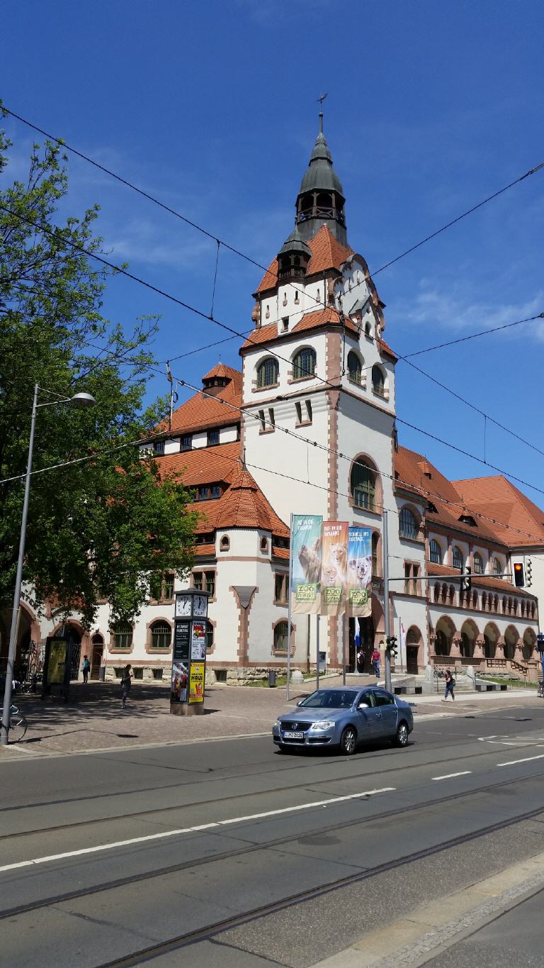 Ein Auto fährt eine Straße entlang vor einem großen Gebäude mit einem Uhrenturm.