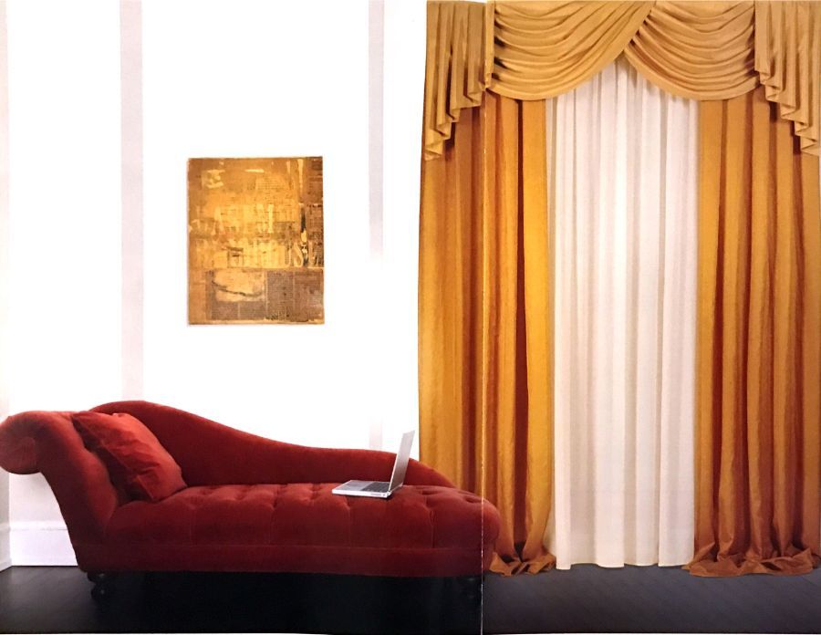 In una stanza bianca, una chaise longue di velluto rosso con un computer portatile è posizionata vicino a tende dorate e a un'opera d'arte murale dorata con una texture particolare.