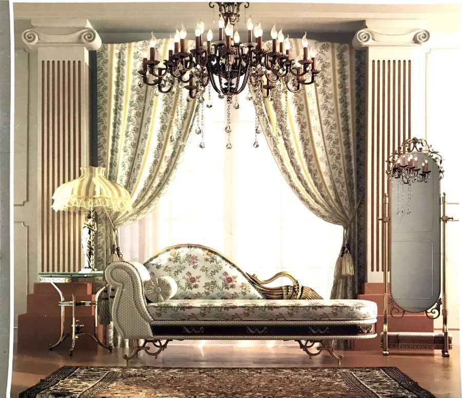 Una chaise longue a motivi floreali è posizionata al centro di una stanza con colonne scanalate, un lampadario, tende decorate e uno specchio a figura intera.