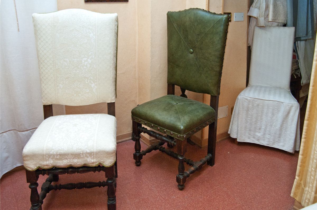 In una stanza ci sono tre sedie in stile vintage, di cui una con rivestimento bianco, una in pelle verde e una con fodera rimovibile.