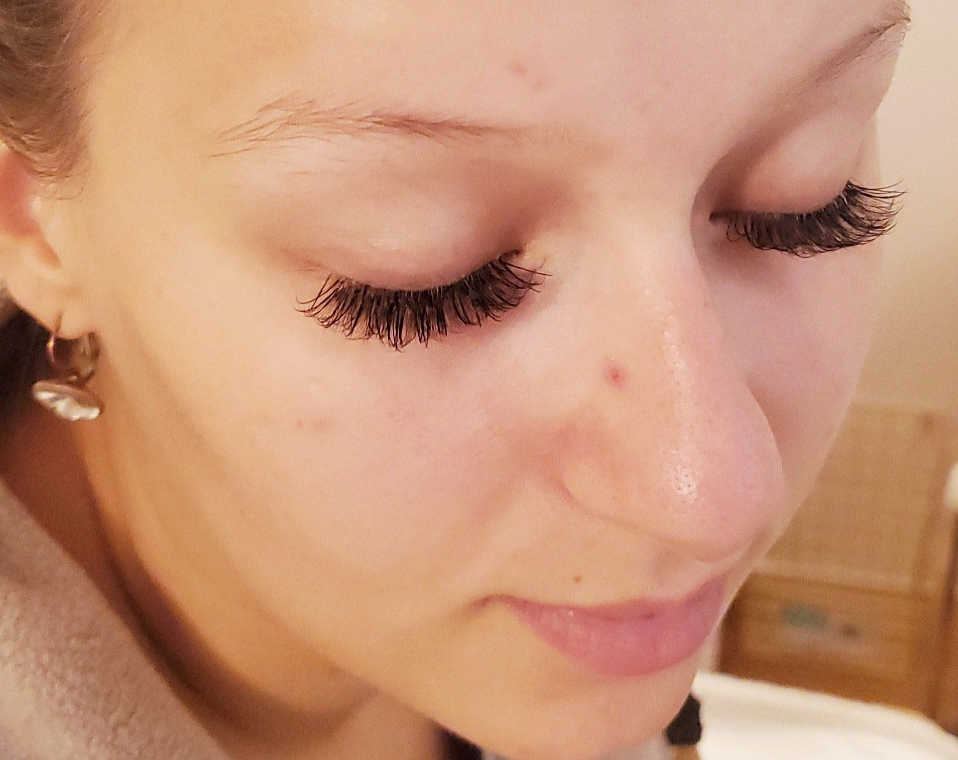 Woman with closed eyes and long, dark eyelashes, small nose, and fair skin.