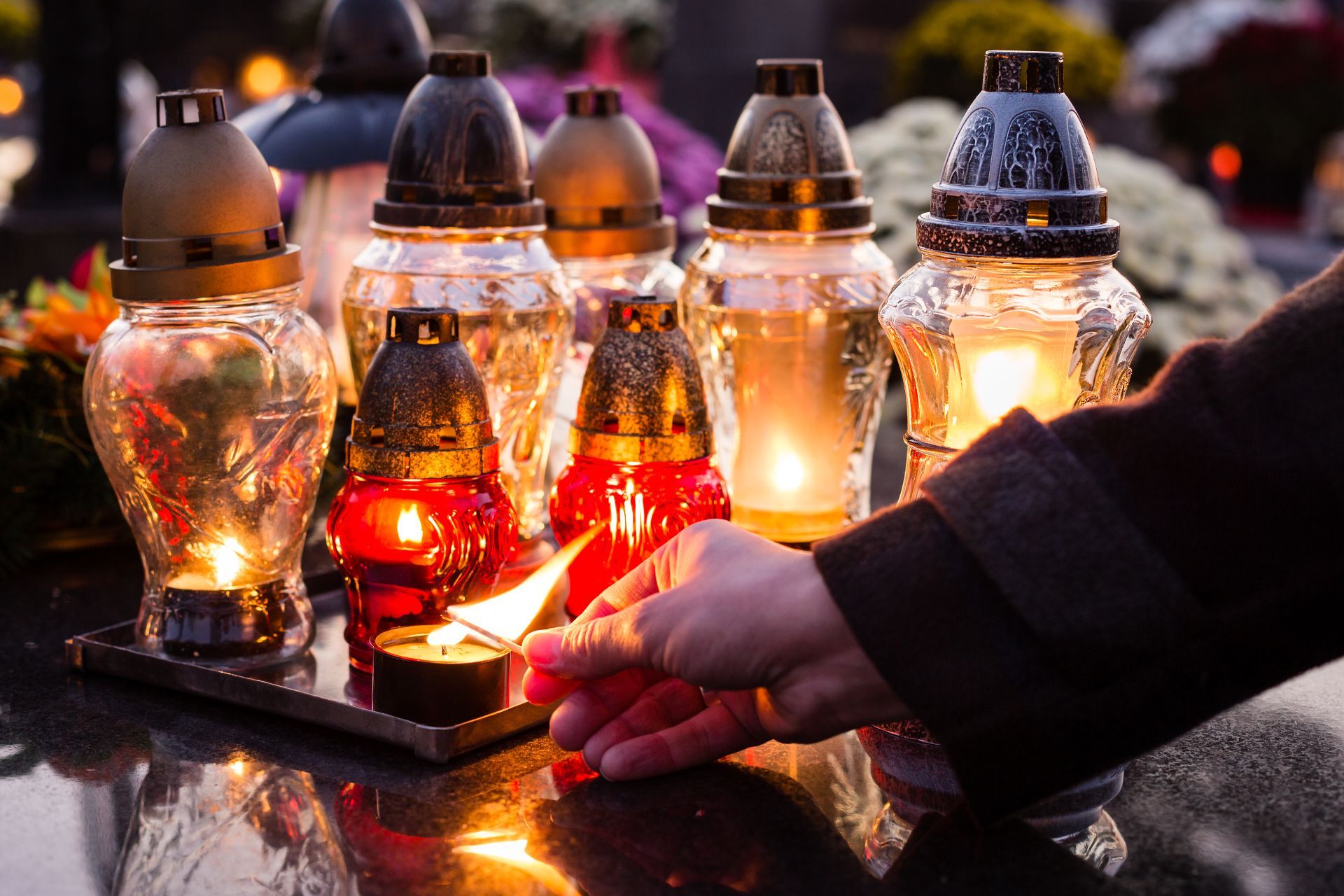 Mano che accende lumino mortuario