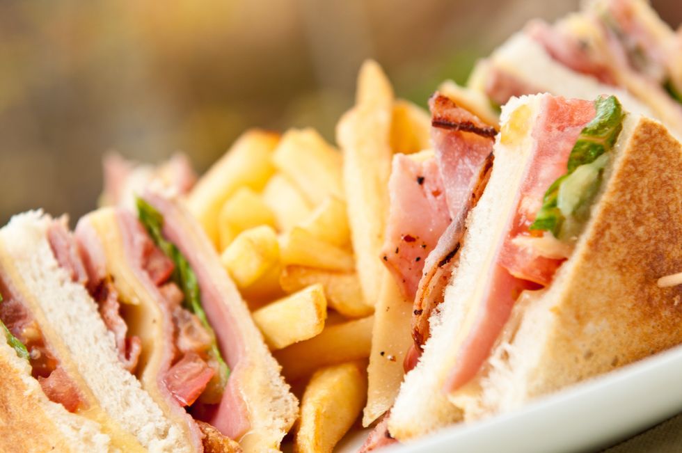 A close up of a club sandwich and french fries on a plate.
