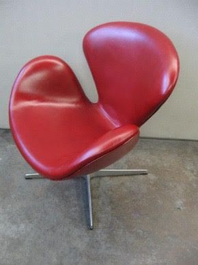 A red chair is sitting on a concrete floor