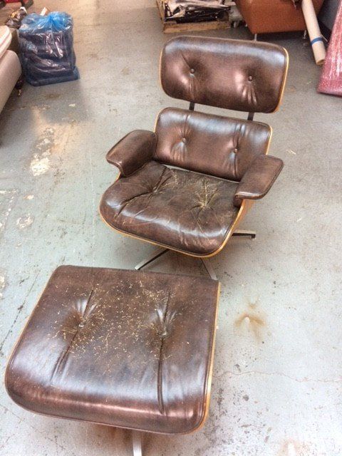 A brown leather chair and ottoman are sitting on a concrete floor