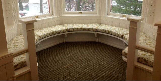 A room with a round bench in front of a window.