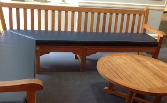 A wooden bench with a blue cushion sits next to a wooden table
