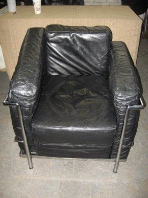 A black leather chair is sitting on a tiled floor next to a table.