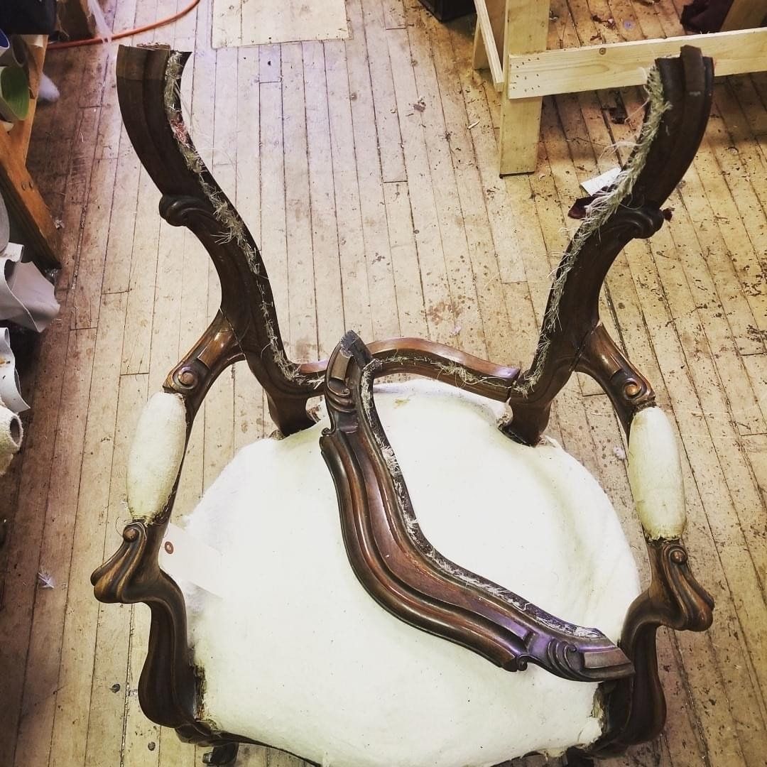 A chair with a broken arm rest is sitting on a wooden floor