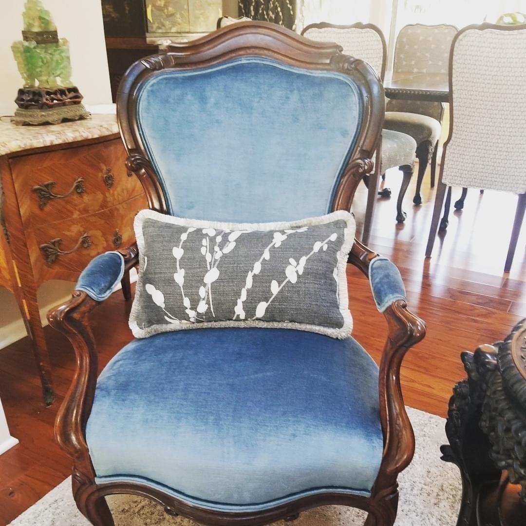 A blue chair with a grey pillow on it