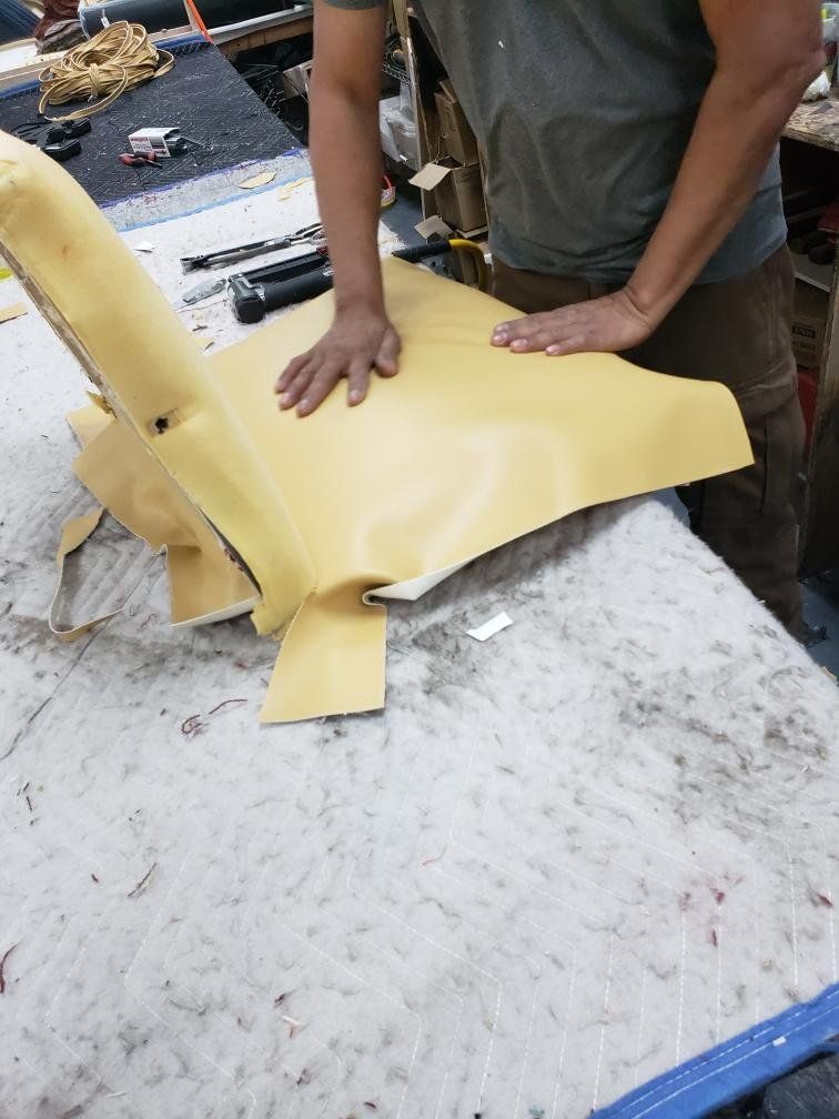 A man is working on a piece of yellow leather