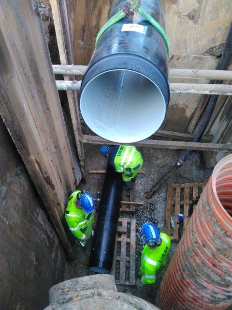 A group of construction workers are working on a large pipe.