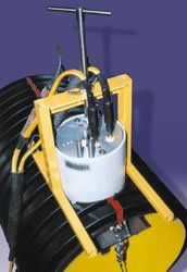 A yellow and white machine is sitting on top of a black pipe.
