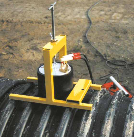 A yellow device is sitting on top of a black pipe