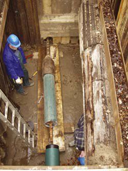 A man is working on a pipe in a trench.