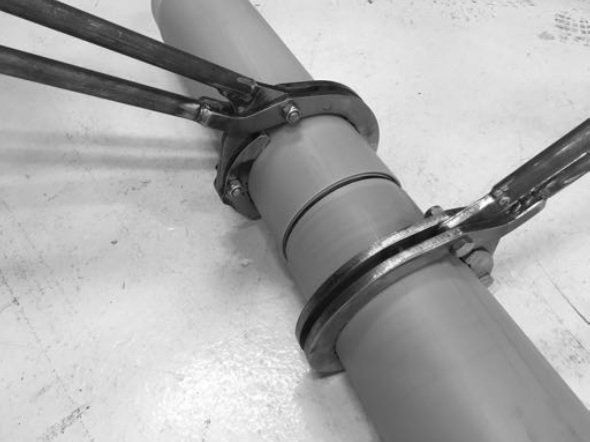 A black and white photo of a pipe with a pair of pliers attached to it.