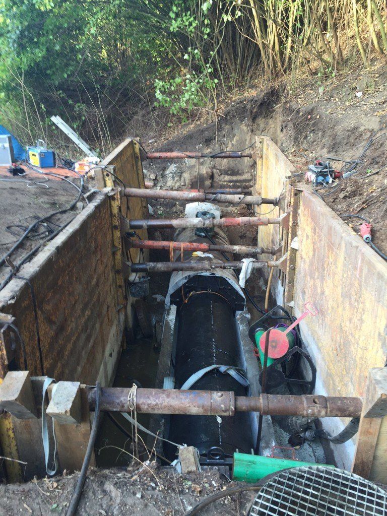 A large pipe is being installed in a trench.