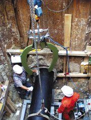 A group of men are working on a pipe in a trench.