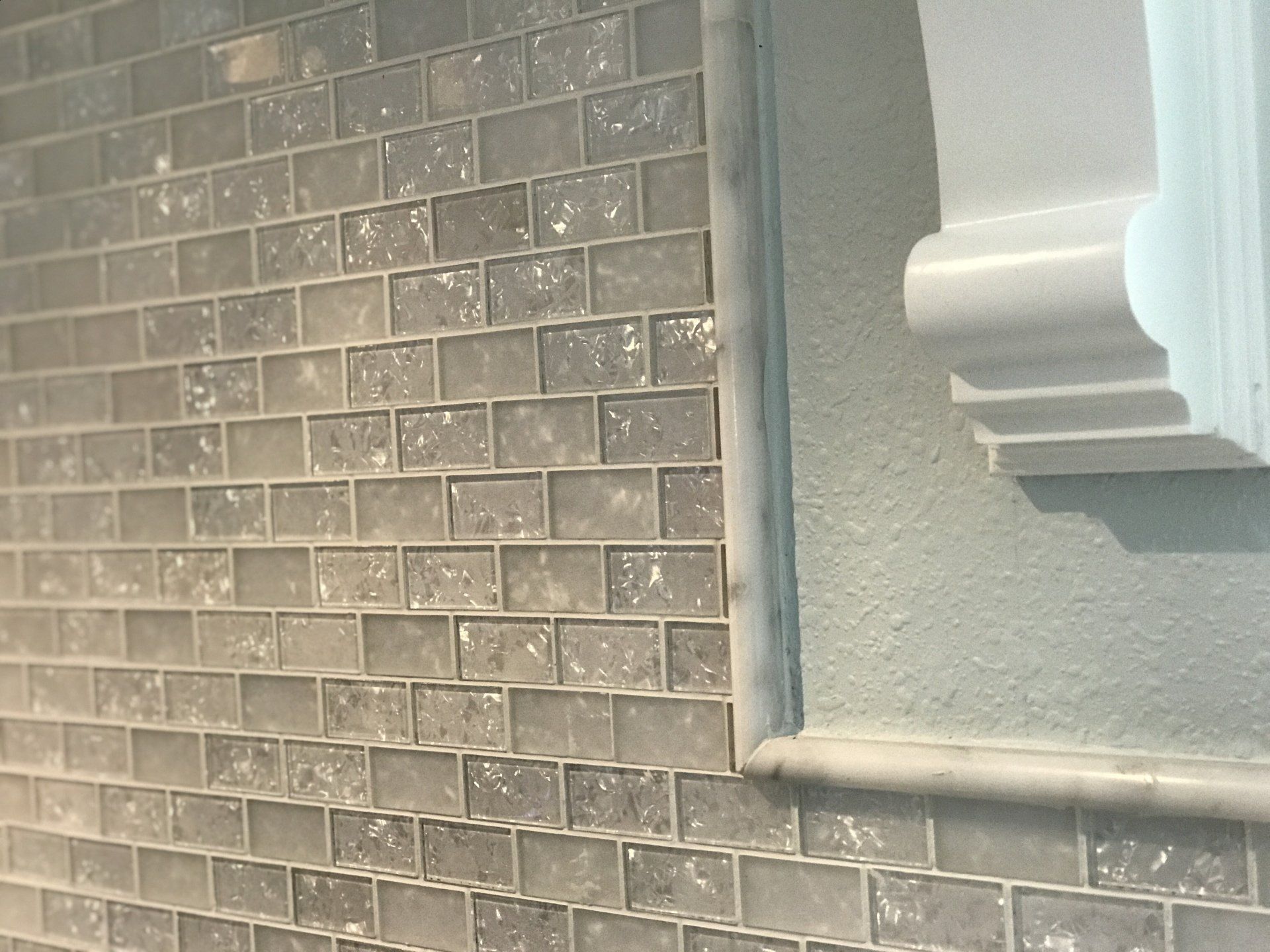Glass tile backsplash with custom wood corbel and bullnose edge tile border