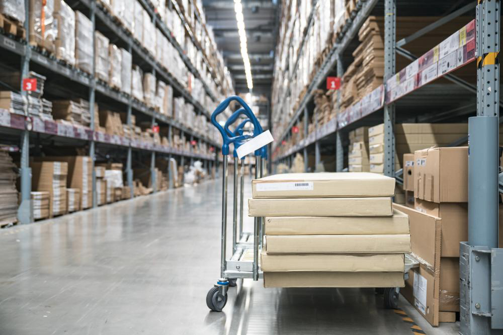 A warehouse filled with lots of boxes and a cart with boxes on it.