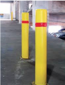 Two yellow poles with red stripes on them are in a parking garage.