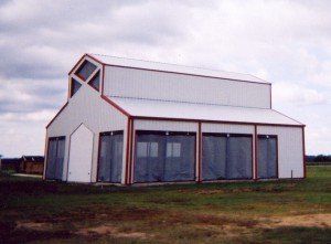 A white barn with a red trim sits in the middle of a grassy field
