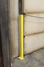A yellow pole is sitting next to a door in a warehouse.