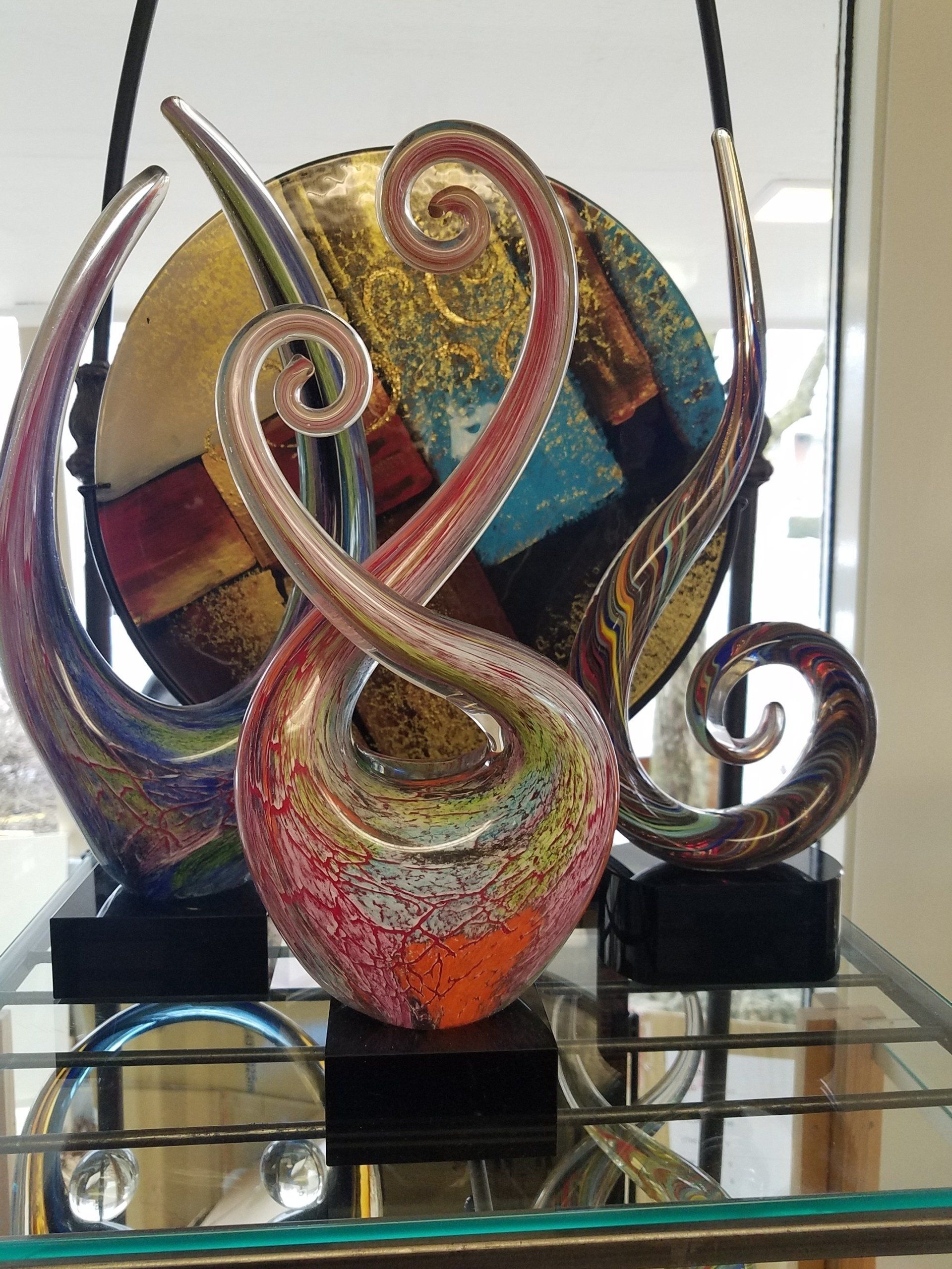 A glass sculpture is sitting on top of a glass shelf.