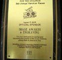 A gold plaque with a picture of a boat on it is hanging on a wall.