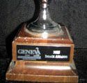 A trophy is sitting on top of a wooden base on a table.