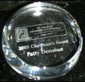 A clear glass paperweight with the name patty donathurt engraved on it.