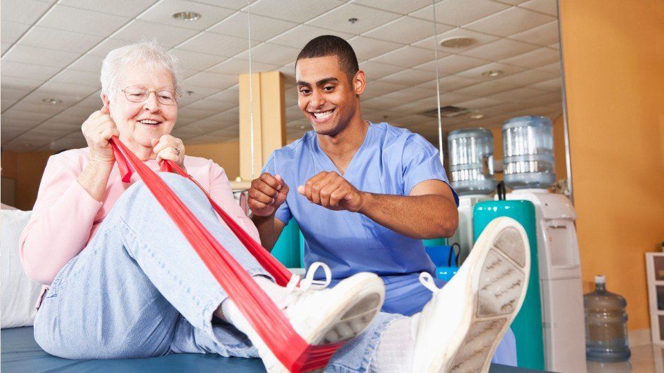 Male nurse with older female patient doing physical therapy exercises