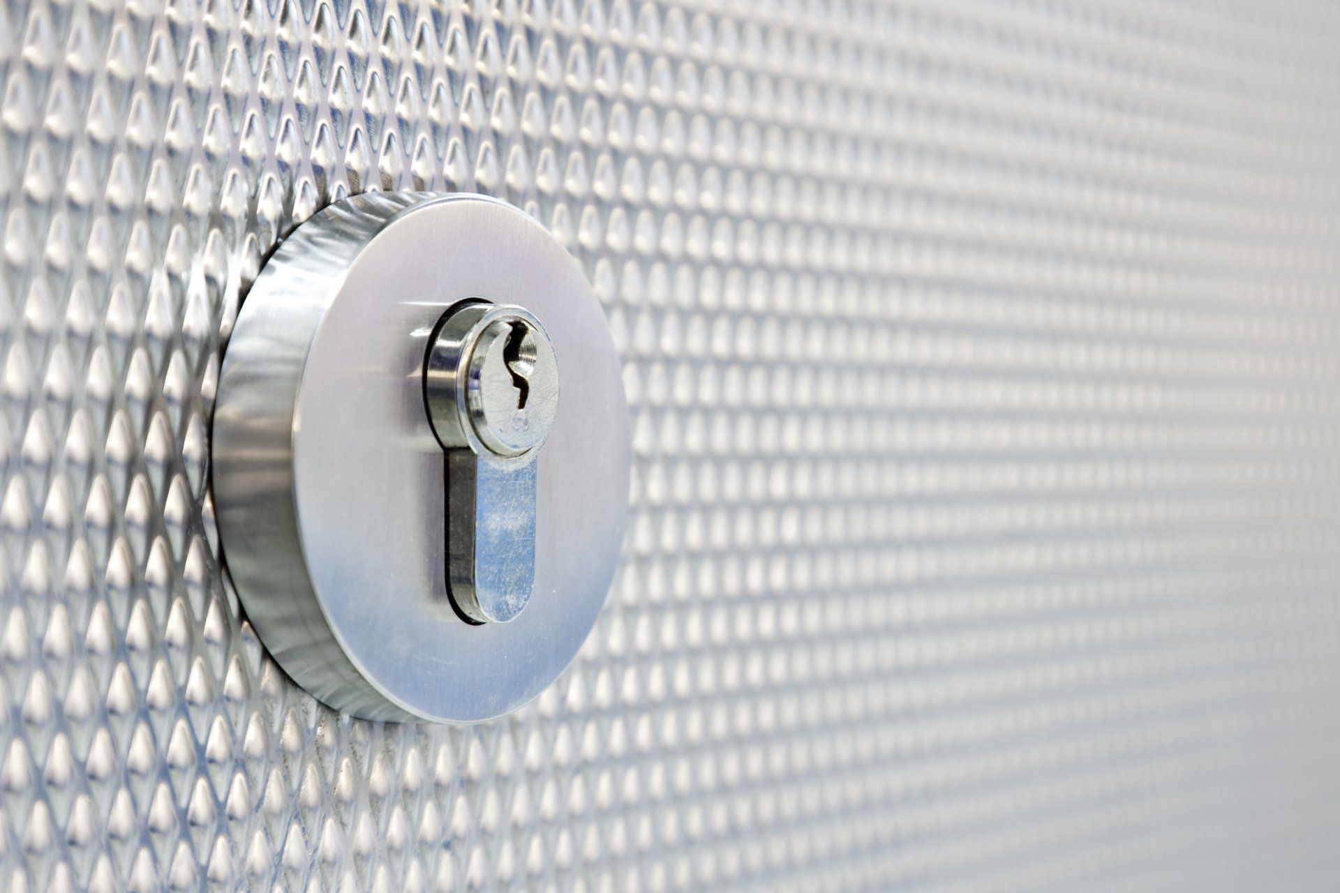 Silver door lock in a metallic, textured door.
