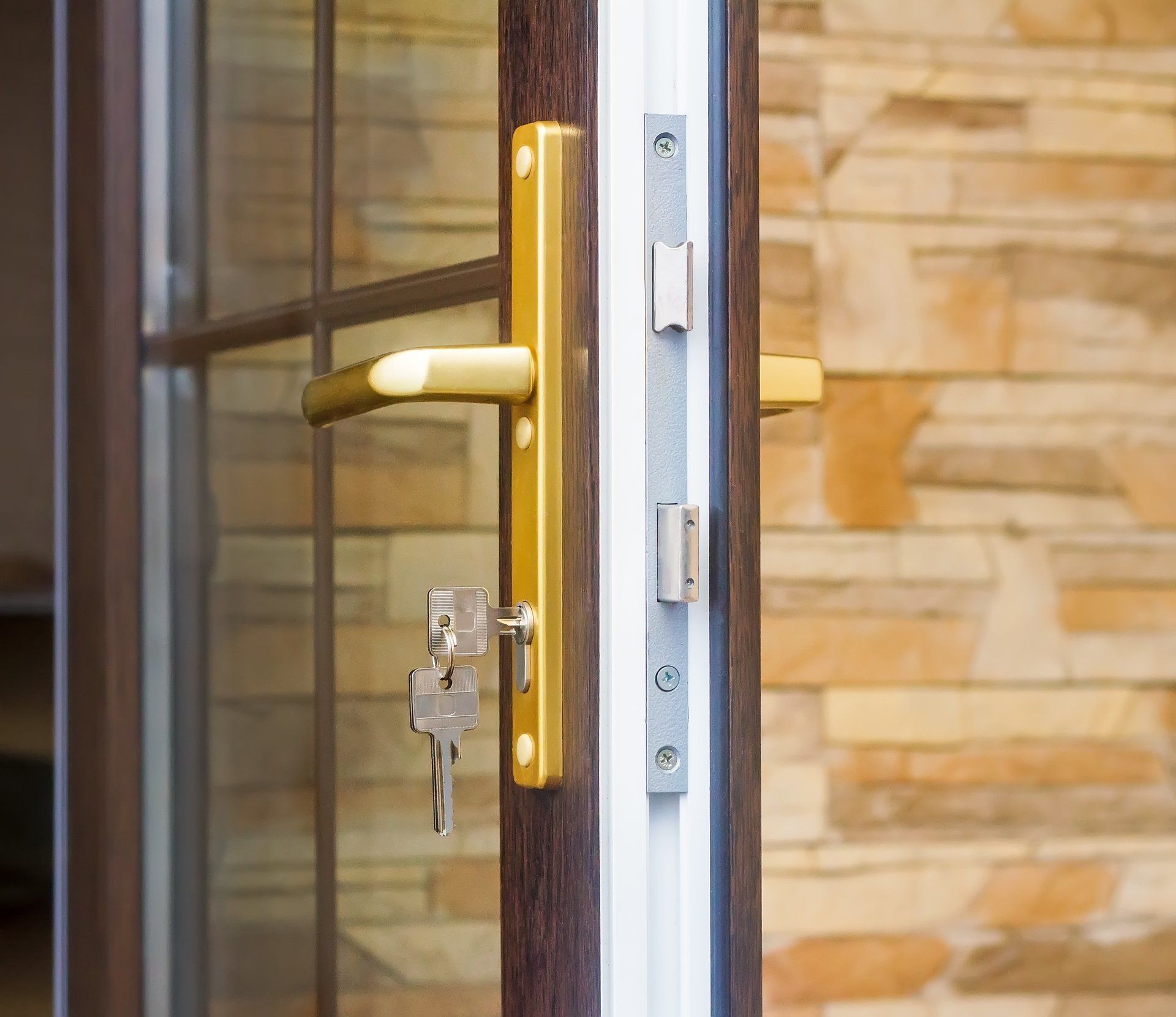 Golden door handle with key in lock; a multi-point lock system is visible on a brown door.