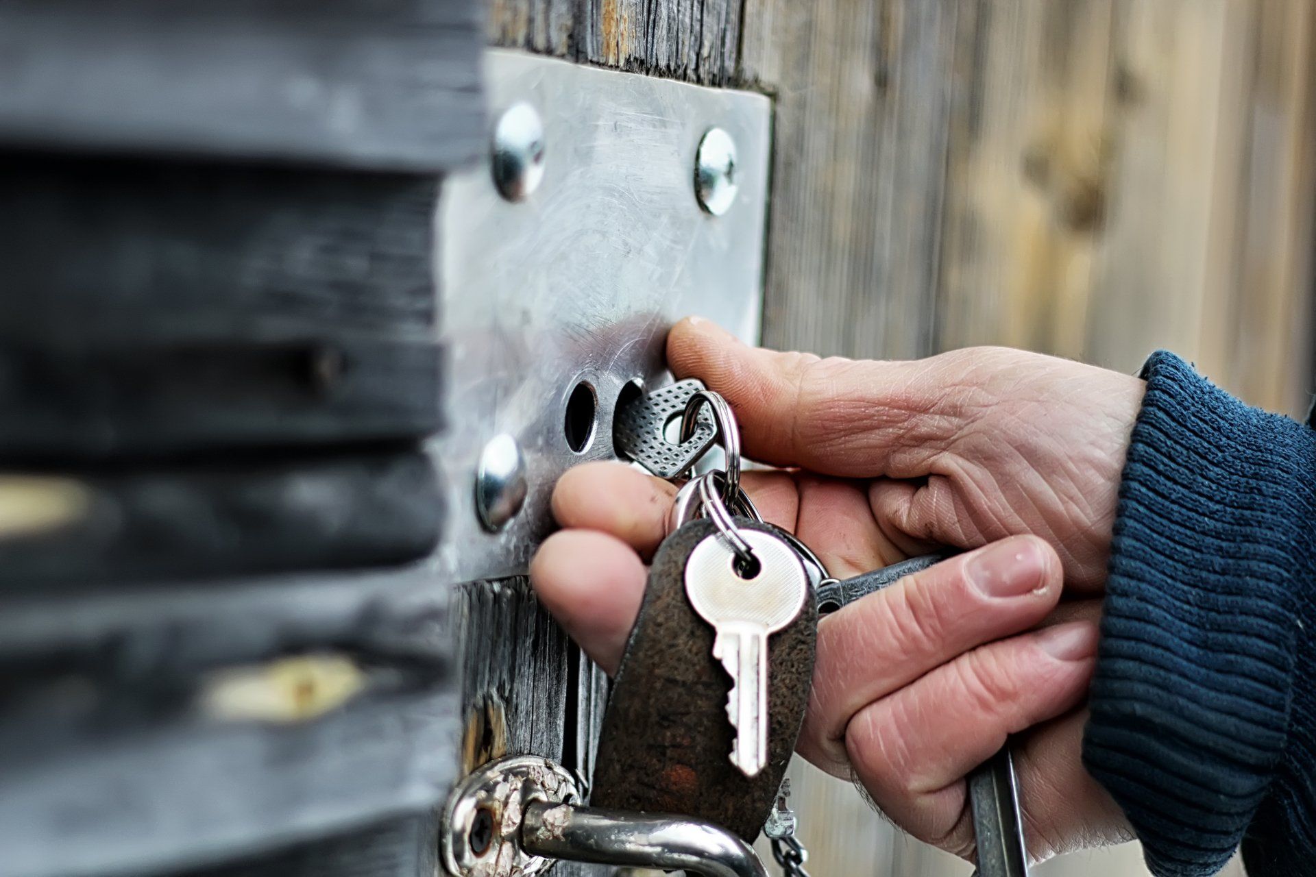 Hand inserting key into a lock on a wooden door.