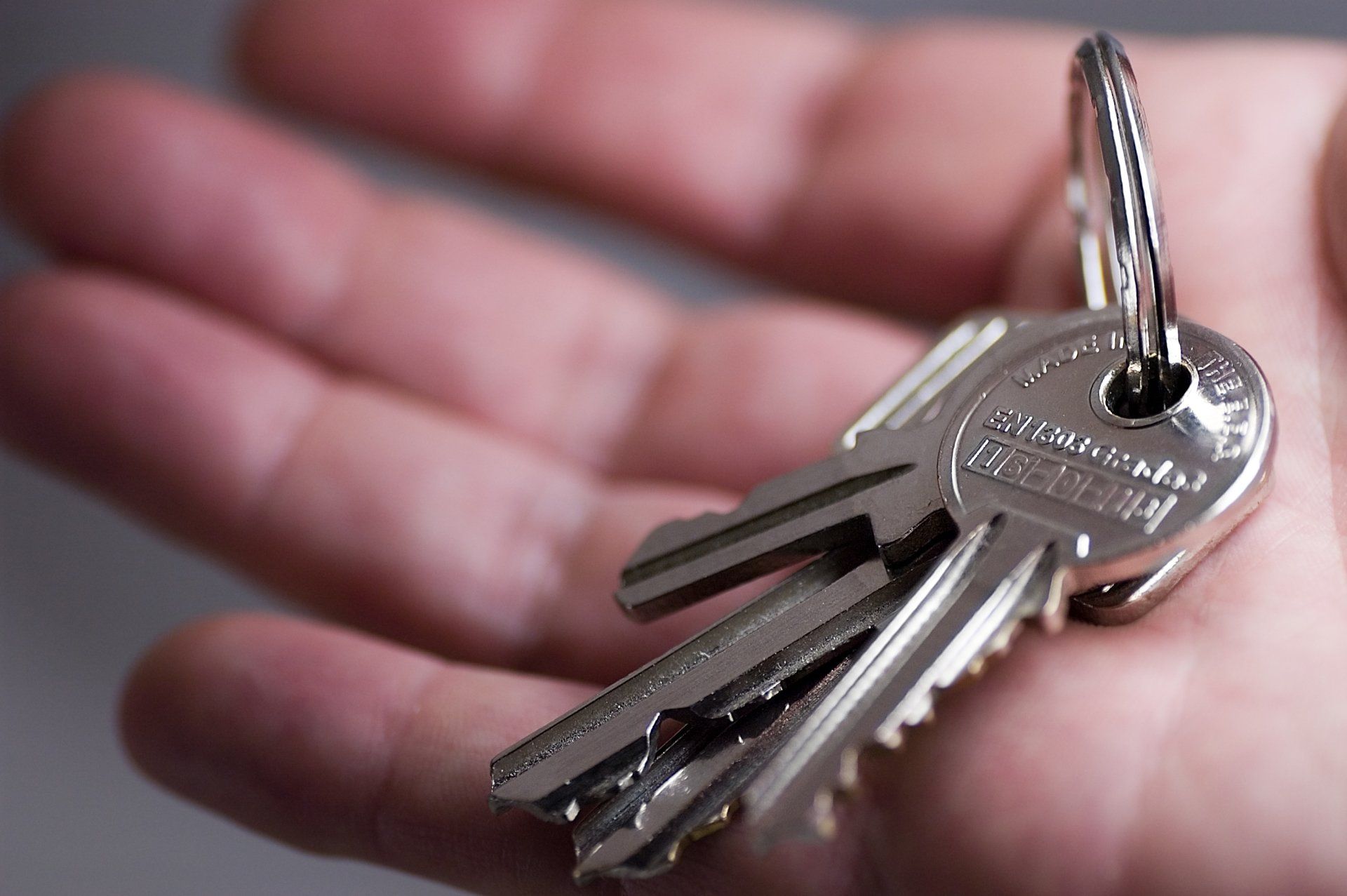 Hand holding a set of silver keys on a key ring.