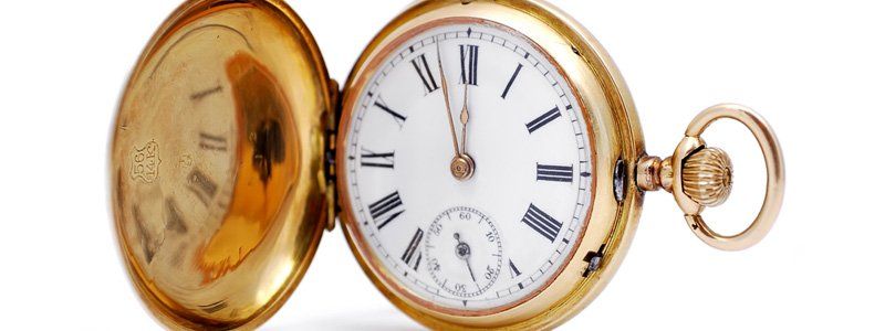 A gold pocket watch with roman numerals on the face