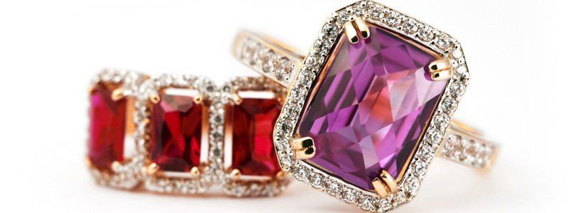 Two rings with purple and red stones on a white background.