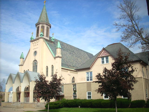 A church with a green steeple and a blue sky in the background