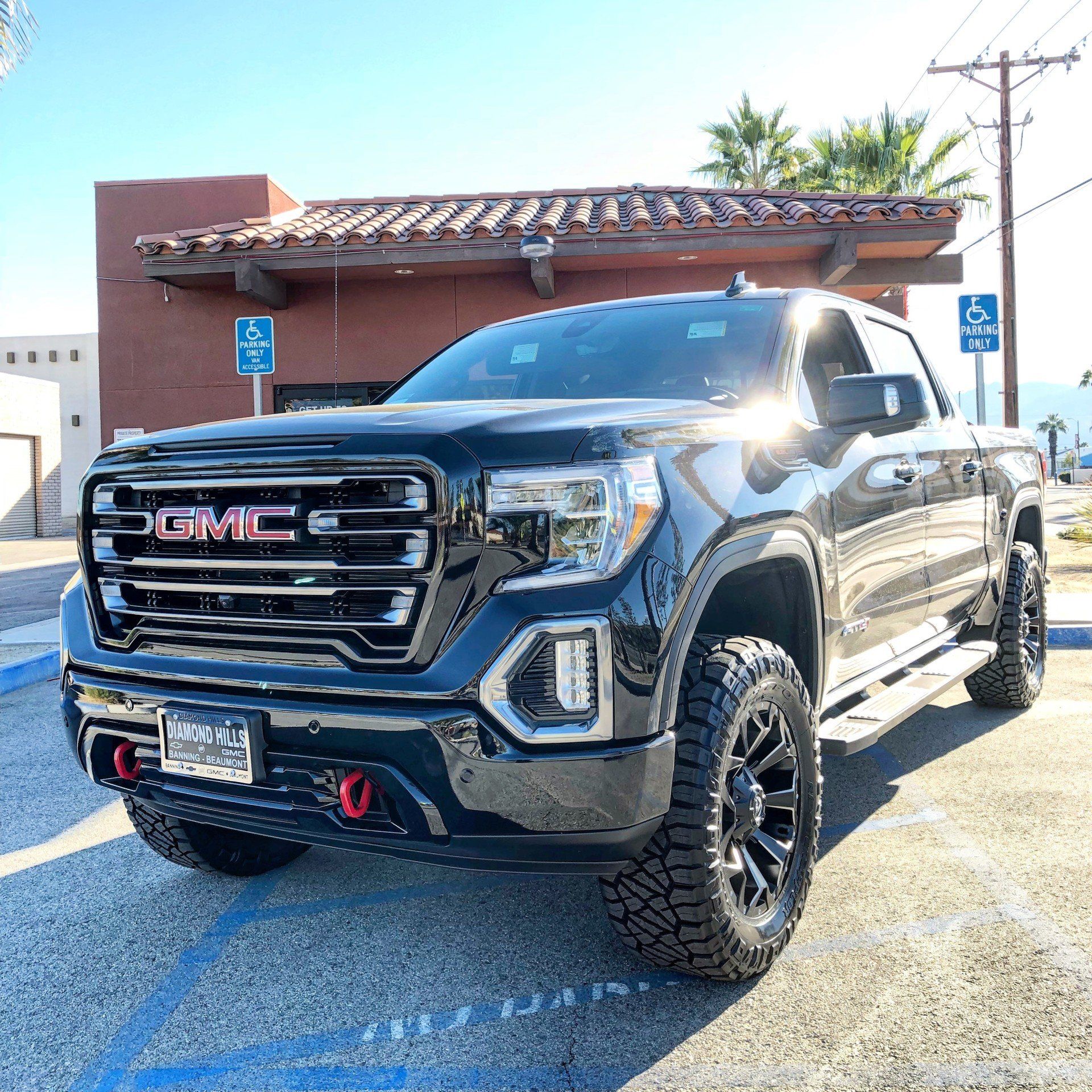 A black gmc truck is parked in a parking lot in front of a building.