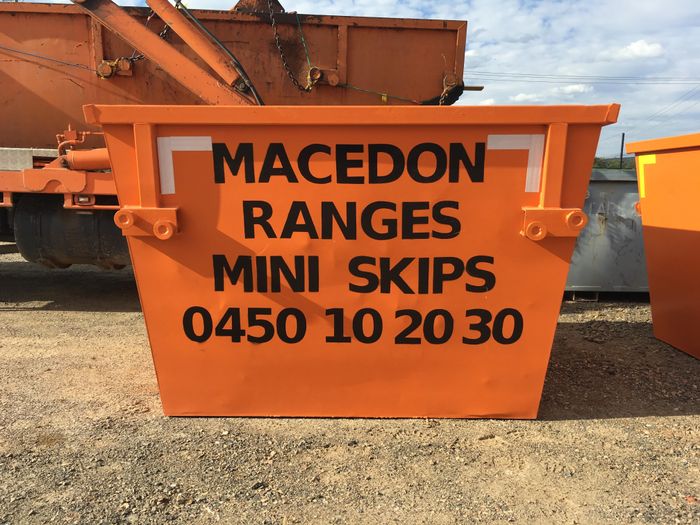 Close up of an orange Macedon Ranges Mini Skips skip bin with contact number