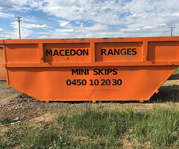 Orange skip bin showing Macedon Ranges Mini Skips branding and phone number