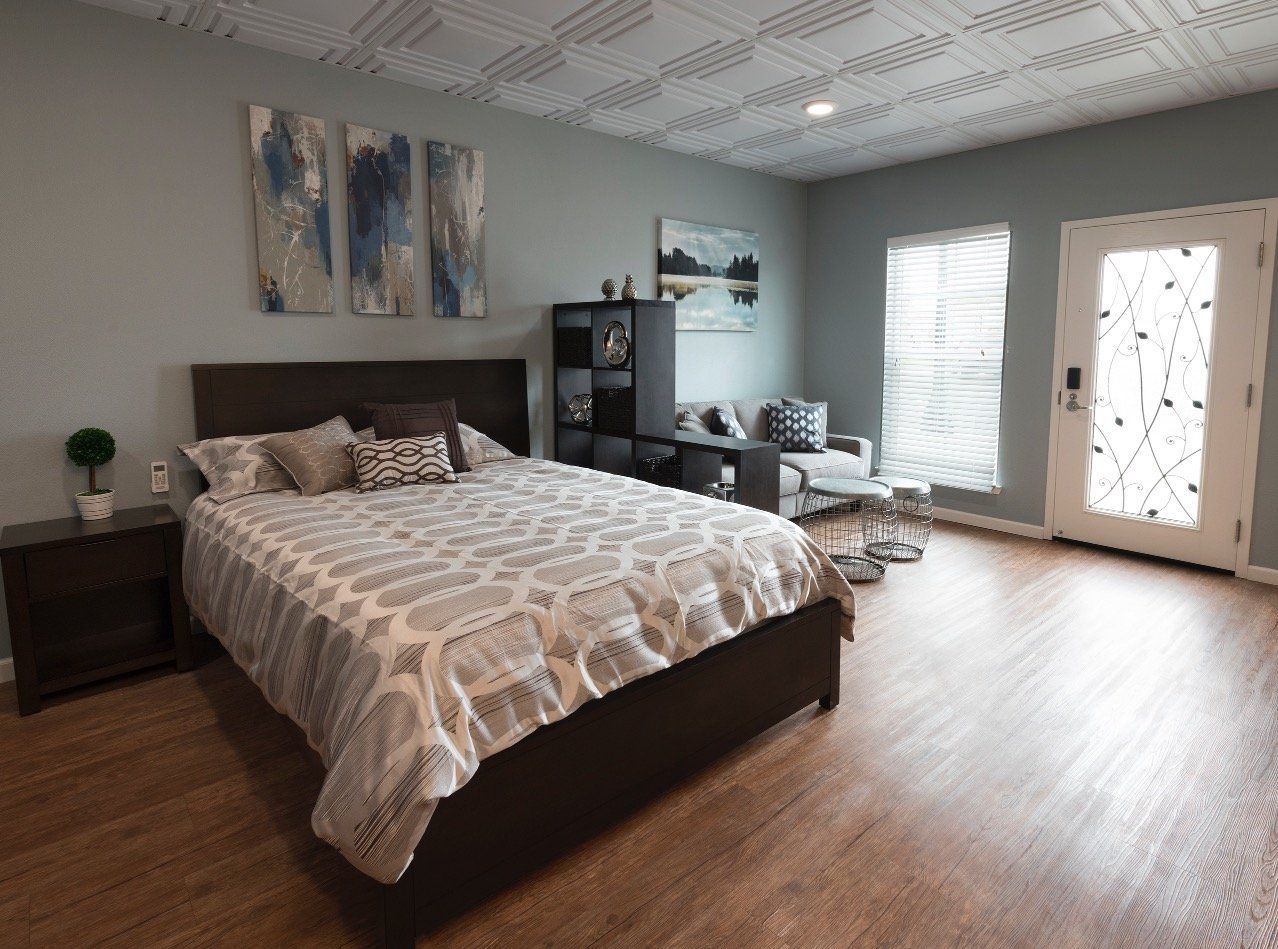 A bedroom with a bed and hardwood floors