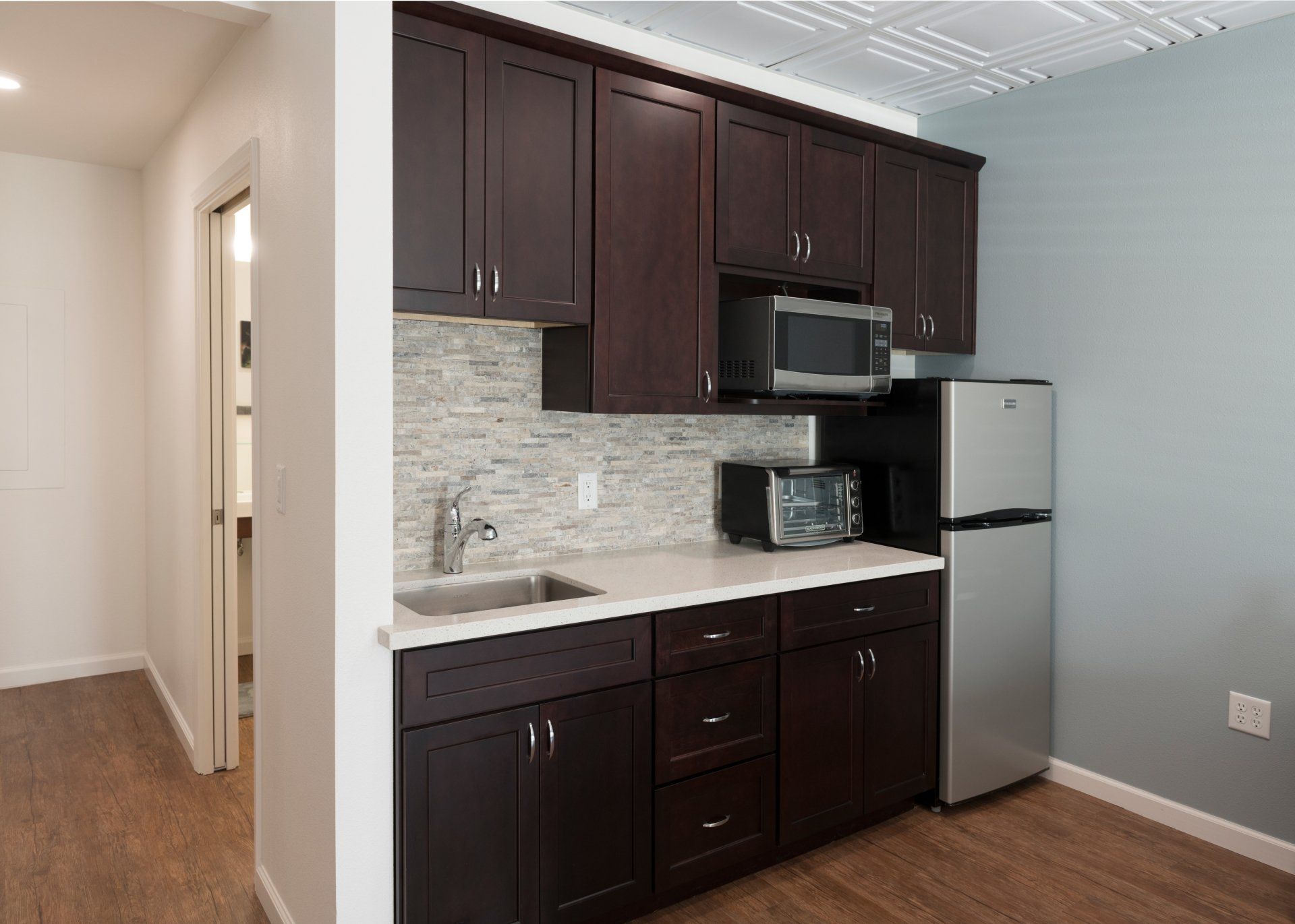 A kitchen with dark cabinets and a stainless steel refrigerator