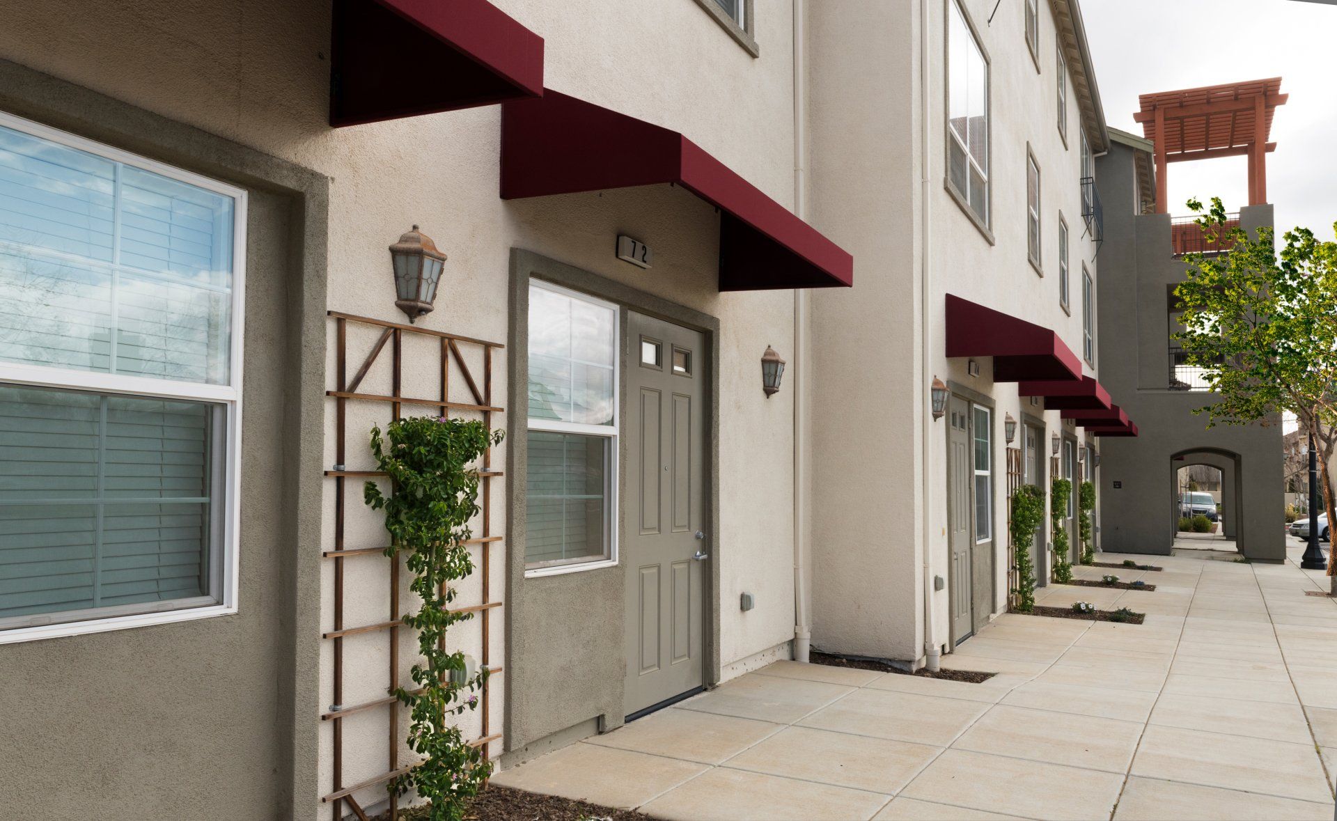 A row of apartments with red awnings over the doors